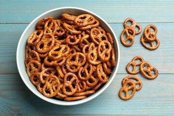 Tasty pretzel crackers on light blue wooden table, top view