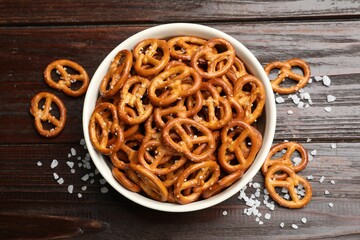 Tasty pretzel crackers with salt on wooden table, top view