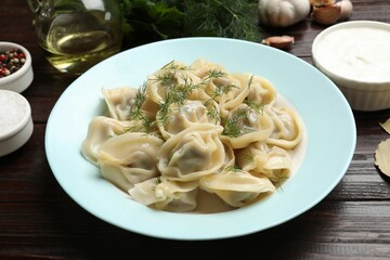 Delicious pelmeni with dill served on wooden table, closeup