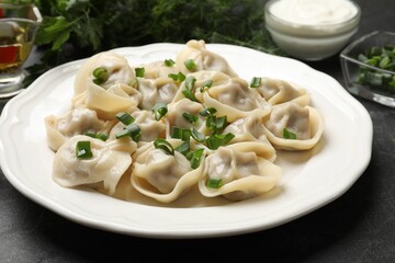 Delicious pelmeni with green onion on grey textured table, closeup