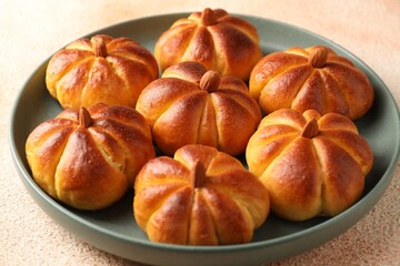 Tasty pumpkin shaped buns on beige textured table, closeup