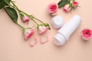 Roll-on deodorant and beautiful rose flowers on beige background, flat lay