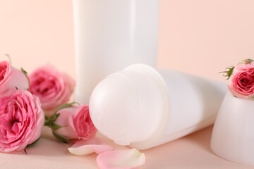 Different deodorants and beautiful rose flowers on beige background, closeup