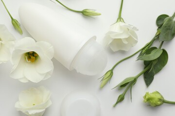 Roll-on deodorant and beautiful eustoma flowers on white background, flat lay