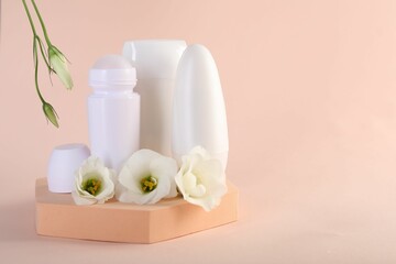 Different deodorants and beautiful eustoma flowers on beige background, space for text