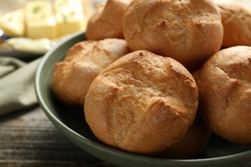 Homemade tasty buns in bowl on wooden table, closeup