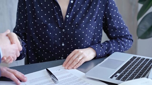 Detailed view of two business people or lawyers signing a contract with a laptop nearby
