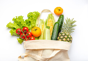 Grocery shopping. Different fresh fruit and vegetables in a textile shopper bag on white background, healthy food from supermarket or delivery concept..
