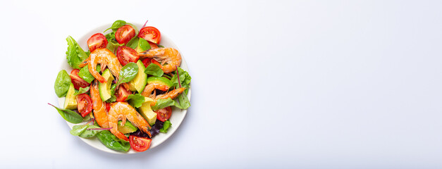 Healthy salad with grilled shrimps, avocado, cherry tomatoes and green leaves on white plate isolated on white background top view. Clean eating, nutrition and dieting concept, space for text..