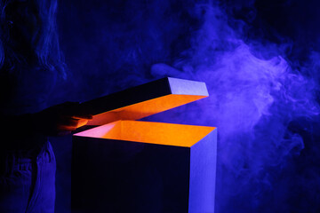Man opens magic box with surprise on dark background, mystical box, surprise, halloween