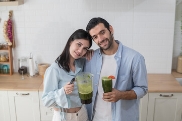 Young couple cooking healthy vegetable blends in the kitchen, they put variety of fruits and vegetables in a blender to make a healthy drink together