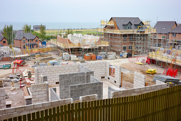 Large construction site with modern residential buildings taking shape near a waterfront.