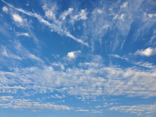 Clear blue sky with fluffy white clouds in a serene, peaceful atmosphere. Perfect weather concept...