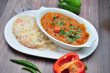 Delicious plate of creamy curry accompanied by fluffy rice., with fresh coriander, and green chilies served with tomato & lemon