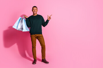 Full length photo of funky cool guy dressed pullover rising bargains pointing emtpy space isolated pink color background