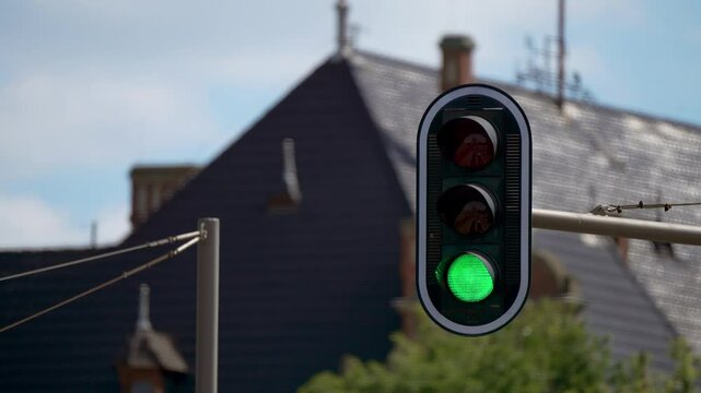 Traffic light semaphore changing from red to green. Streetlight regulate traffic closeup. Traffic Signal Displaying Red and Green Light With Building Rooftops in Background on Sunny Day in Urban