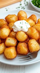 An appetizing center-cut pork chop topped with Greek tzatziki is paired with traditional Spanish potato fritters and dill sauce, beautifully arranged on a white wooden table