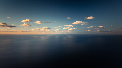  A expansive body of water lies beneath a sky dominated by blue hues and scattered clouds, with an...