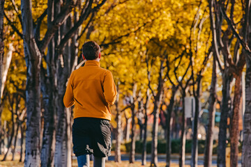 Fototapeta premium A person jogging in a suburban neighborhood with vibrant autumn foliage