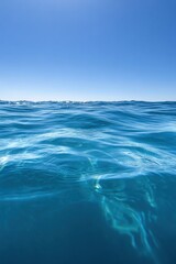 Close-up view of the crystal-clear turquoise ocean sea, with sunlight creating patterns on the water’s surface, reflecting the serenity and purity of tropical seas under a bright, cloud-filled sky.