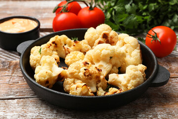 Baked cauliflower, sauce and products on wooden table