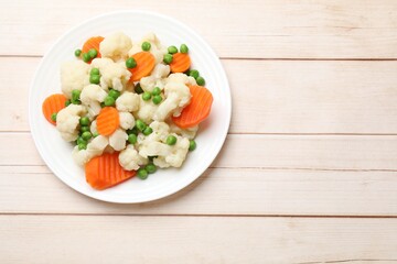 Tasty cooked cauliflower with green peas and carrot slices on white wooden table, top view. Space for text