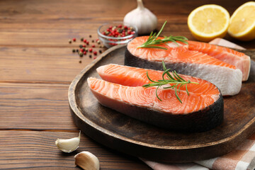 Fresh raw salmon steaks and spices on wooden table, closeup