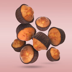 Delicious muffins in air on pink background