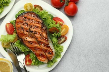 Tasty grilled salmon steak with vegetables served on light grey table, top view. Space for text
