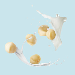Macadamia nuts and splashing milk in air on light blue background