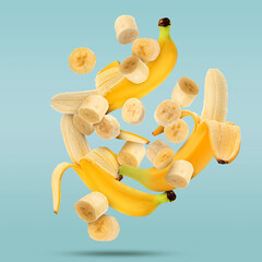 Fresh ripe bananas falling on light blue background