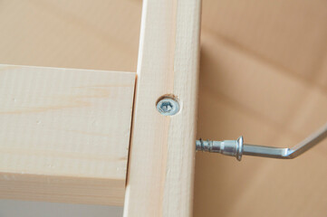 close-up: connecting part of the table legs with one screwed confirmat and a half-screwed confirmat with a hex key in it