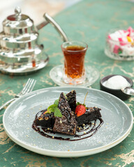 Delicious chocolate brownie slices being served on plate with tea and turkish delight