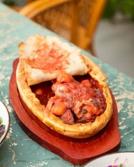 Delicious traditional tajik dish with meat and tomatoes covered with flatbread on wooden plate