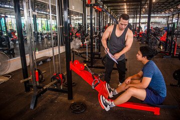 Male trainer shows the exercise program to the trainee and plans the exercise plan for the trainee.