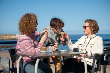 Three generations family sharing ice cream and coffee at a seaside café