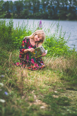 girl with long blond hair outdoors reading a book