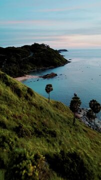 Vertical Video - Lush green mountains near the sea during a sunset