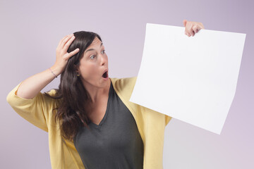 Naklejka premium Woman holds a blank poster and looks at it with a surprised face