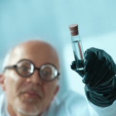 Scientist wearing a black glove holding a test tube with a stran