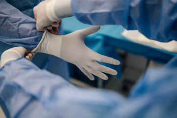 Close-up of healthcare professionals donning surgical gloves.
