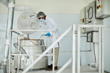 Side view of African American male technician with digital tablet in hands looking inside of large...