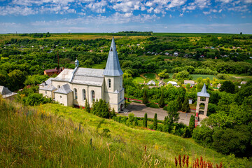 Catholic church in the Ukrainian village of Zinkiv. Rural landscape with a beautiful church on a summer day.