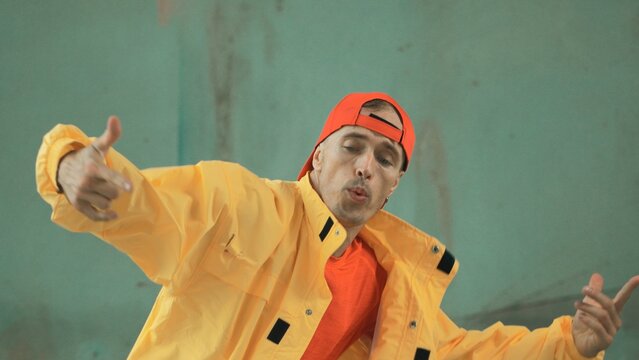 Closeup image of caucasian hipster shows or practicing footstep at street, urban city. Motion shot of young stylish break dancer moving arm and leg. Outdoor sport 2024. Gray background. Hiphop.