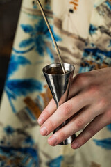 Close-up of bartender pouring alcohol into a jigger