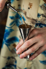 Close-up of bartender pouring alcohol into a jigger