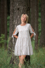 Portrait of a young beautiful blonde girl in a dress in nature.