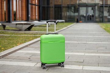 Closeup shot of Cabin Baggage suitcase standing on city street background. Travel Fashion.