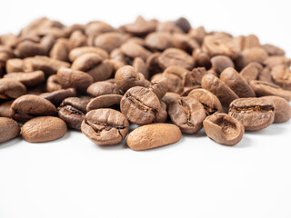 close-up of roasted arabica coffee beans lie on a white background.
