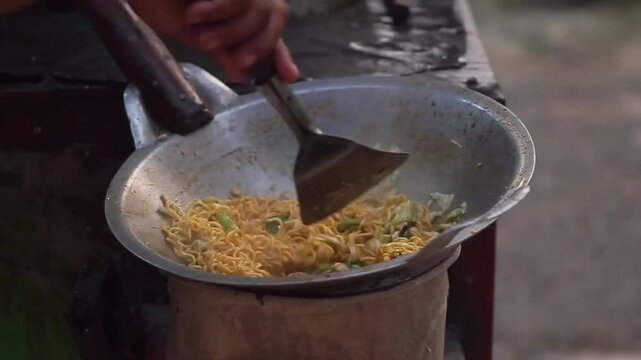 Cooking dried noodles into boiling water in a pan on a charcoal stove. Traditional food from Java, Indonesia